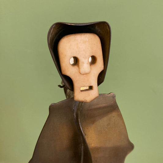 Sculpture représentant une vanité ou ne tête de mort en os, sur une base en métal en forme de flamme.