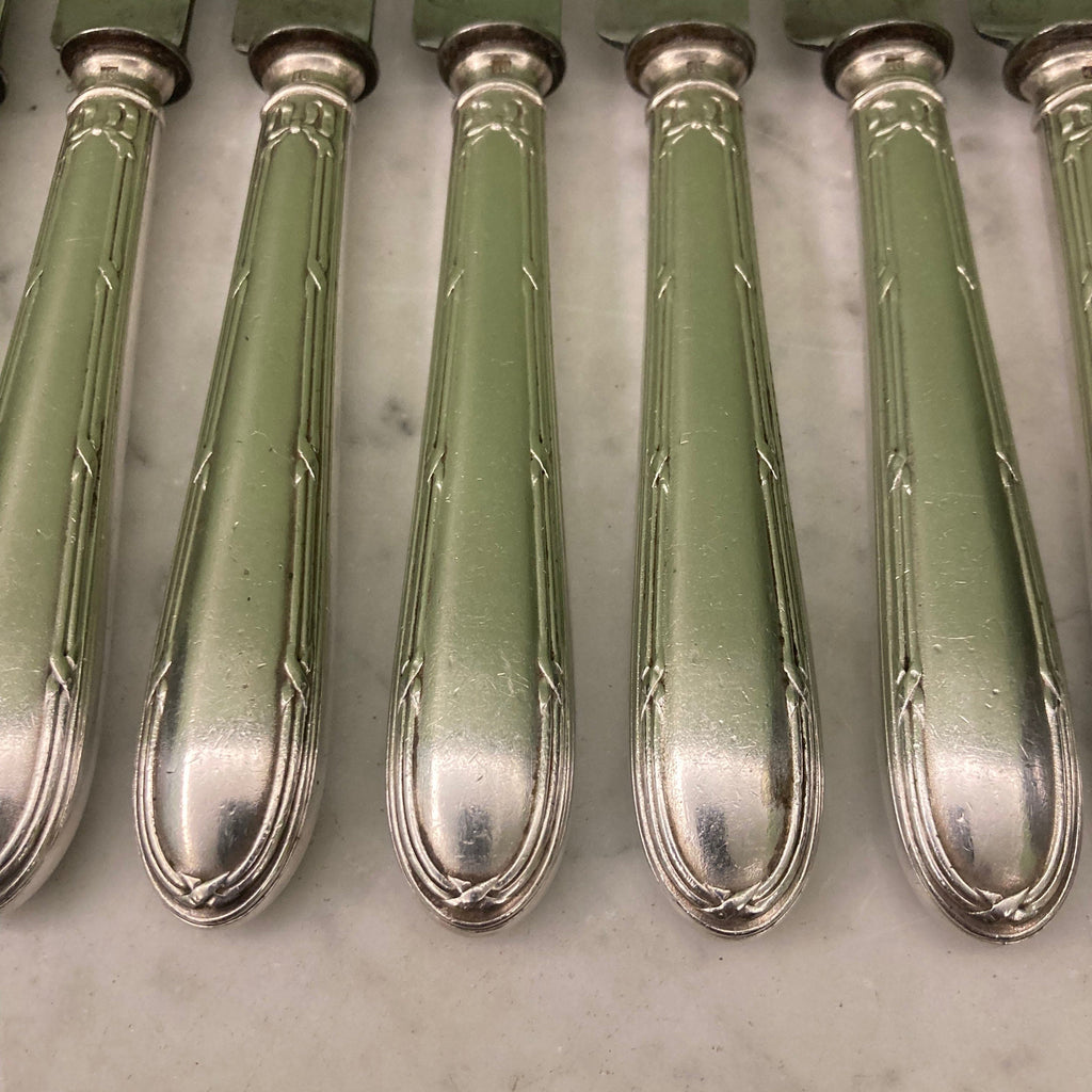 12 couteaux à entremets en métal argenté et lames acier. Modèle rubans croisés. Marque: Au Lion