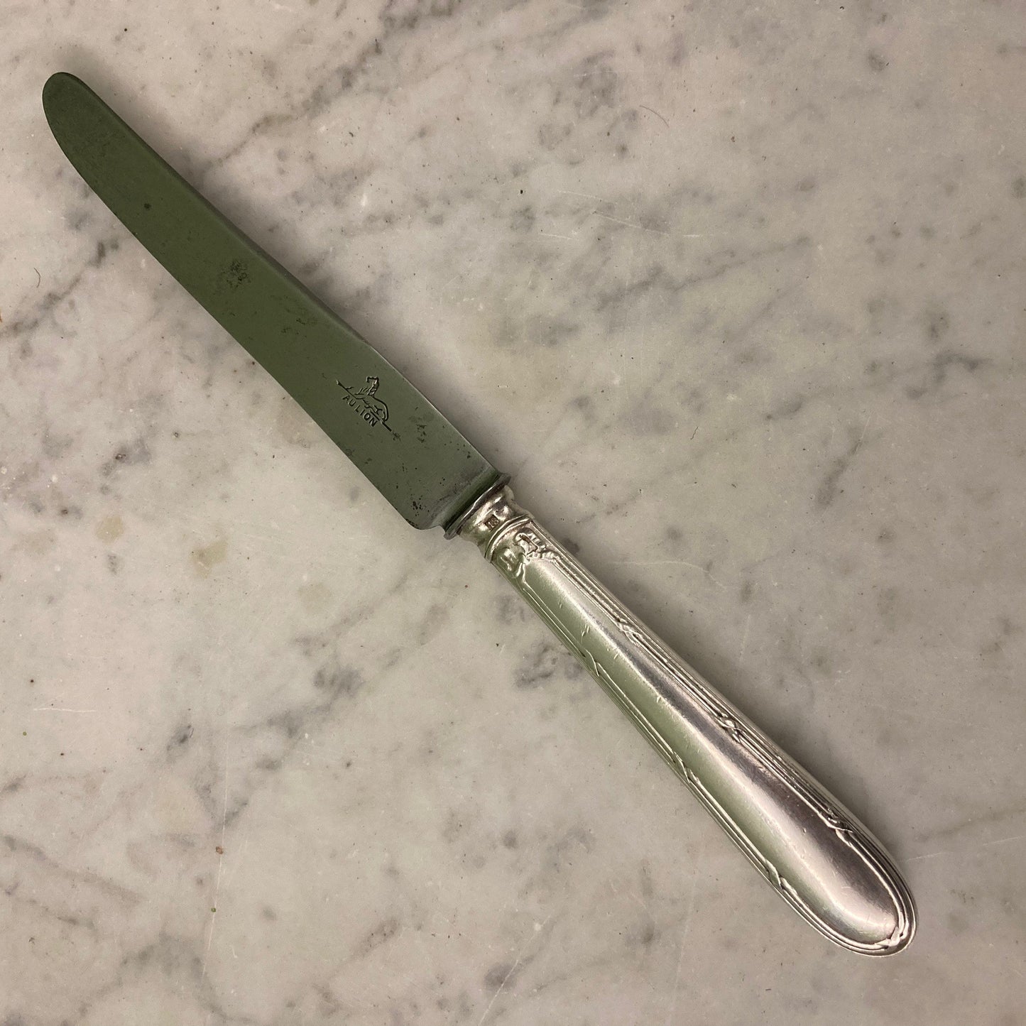 12 couteaux à entremets en métal argenté et lames acier. Modèle rubans croisés. Marque: Au Lion