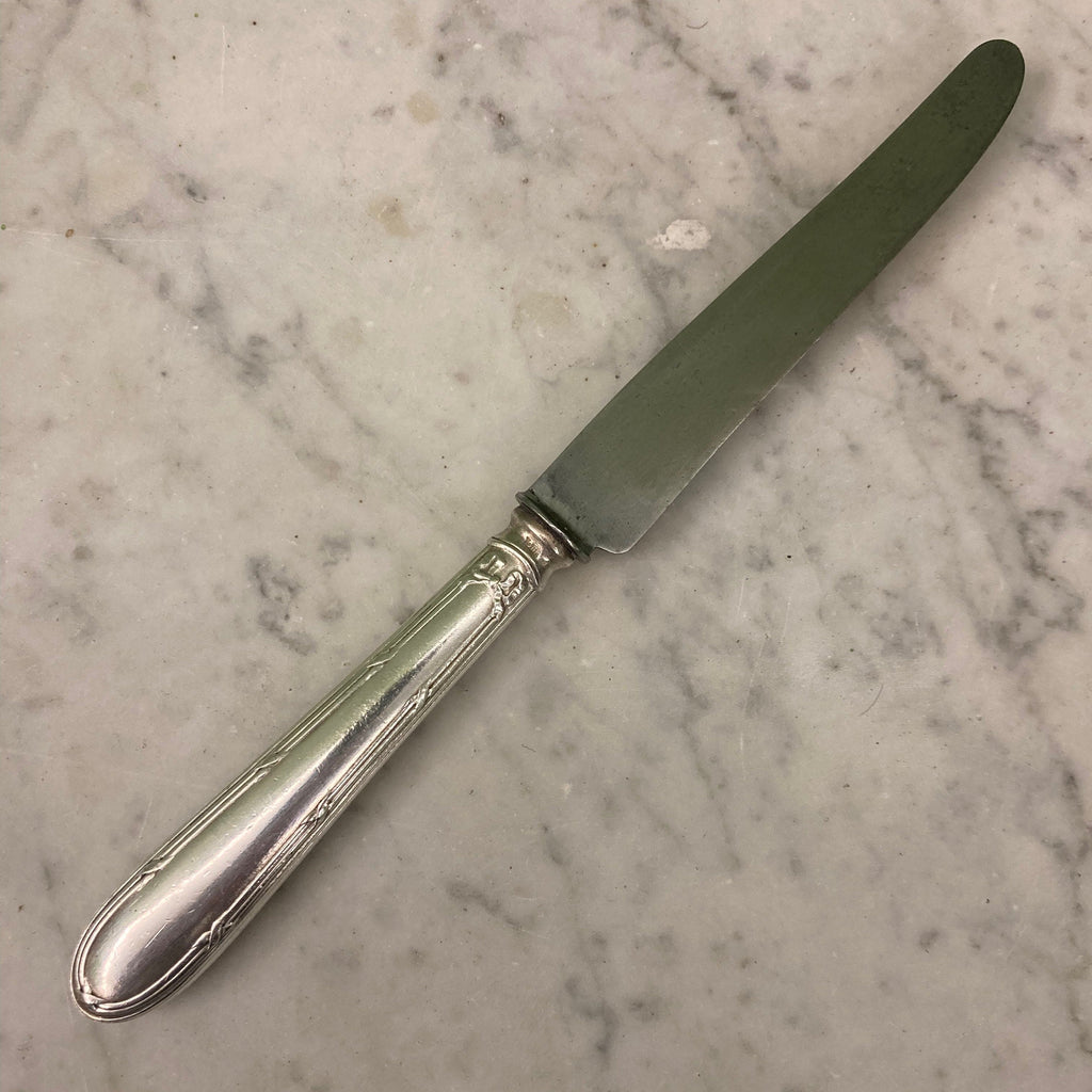 12 couteaux à entremets en métal argenté et lames acier. Modèle rubans croisés. Marque: Au Lion