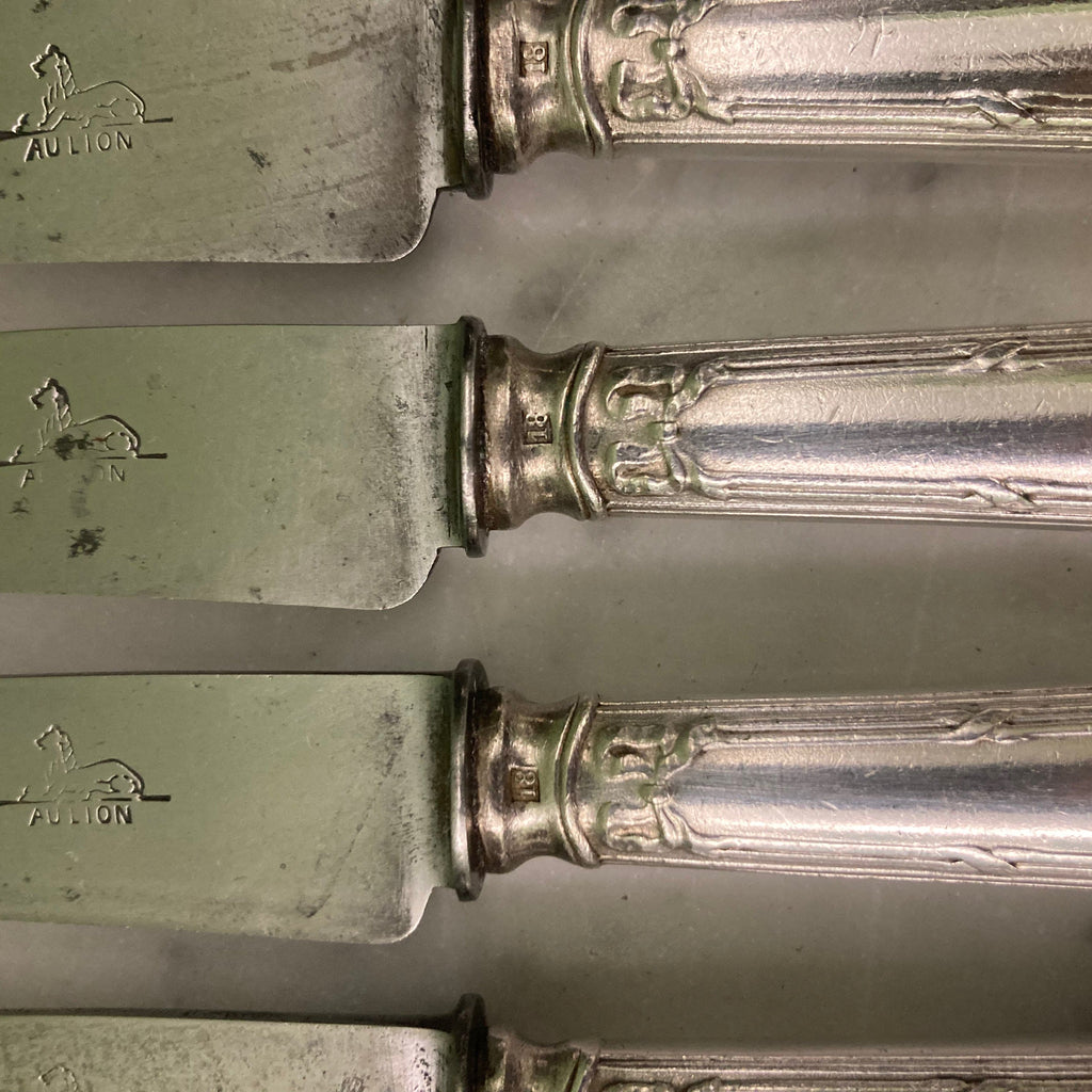 12 couteaux à entremets en métal argenté et lames acier. Modèle rubans croisés. Marque: Au Lion