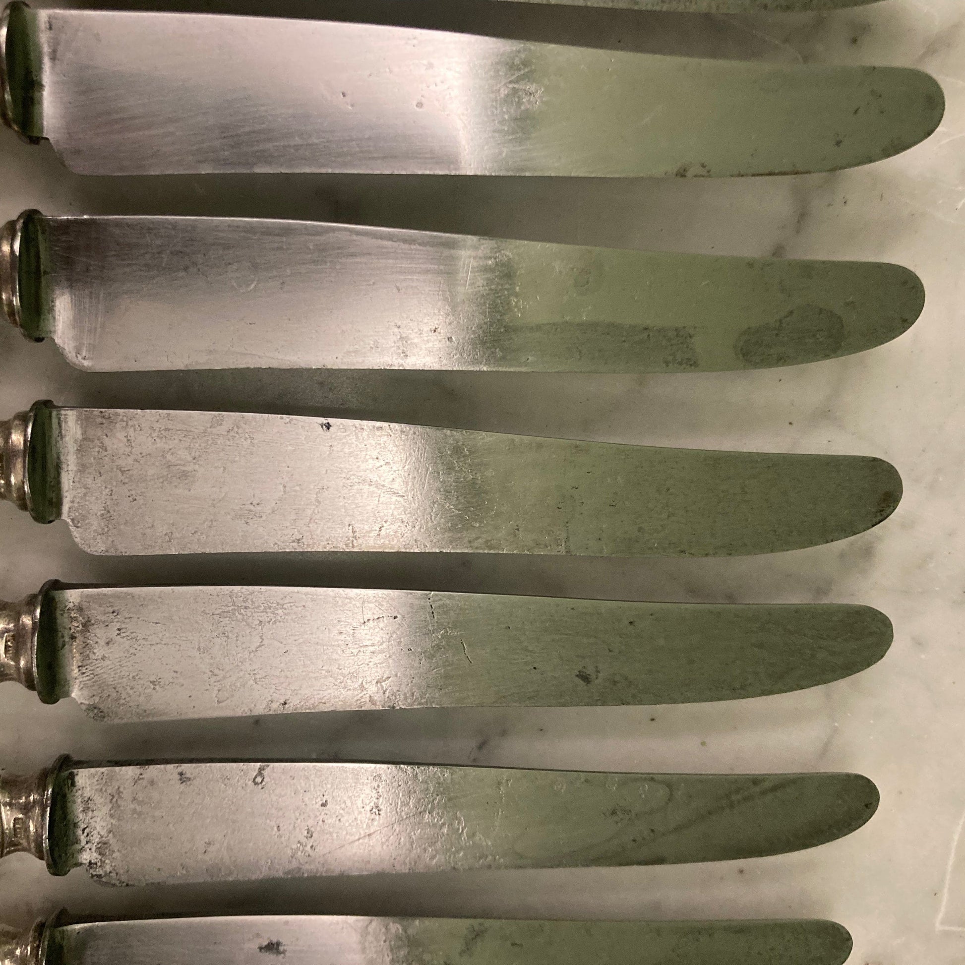 12 couteaux à entremets en métal argenté et lames acier. Modèle rubans croisés. Marque: Au Lion