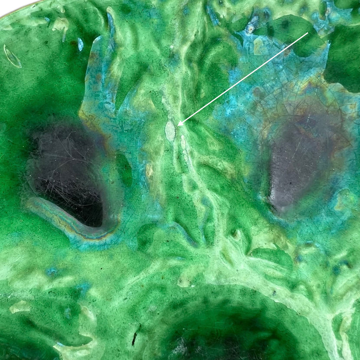 Détail d' une égrenure sur une assiette à huîtres Foucard Jourdan Vallauris en céramique émaillée verte, décor vintage Vallauris à six compartiments.