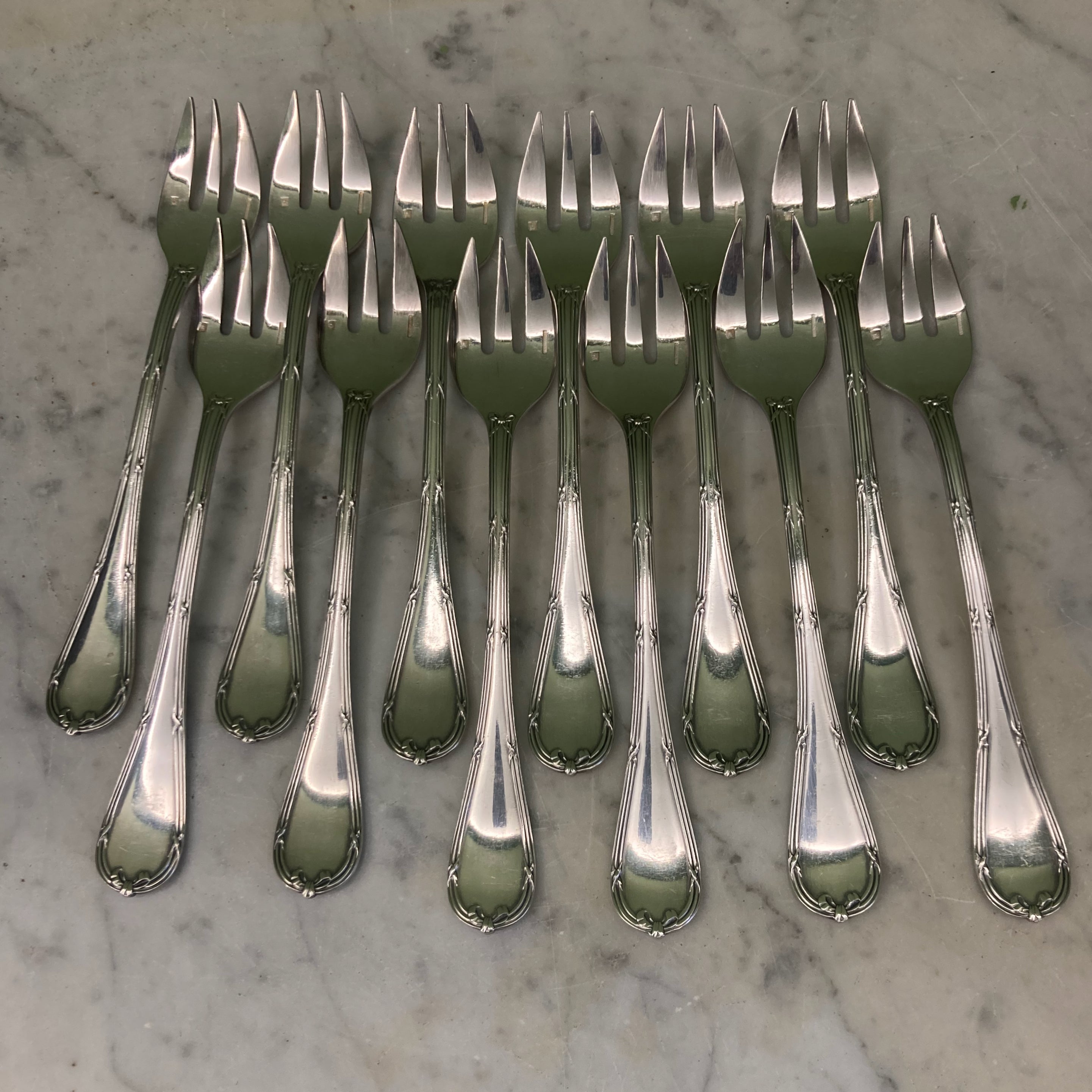 12 fourchettes à huitres de chez Christofle en métal argenté modèle rubans croisés.