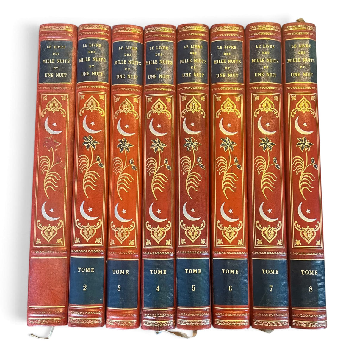 Collection complète de huit volumes du Livre des Mille Nuits et Une Nuit de Mardrus, reliés en demi-veau rouge avec décor oriental doré.