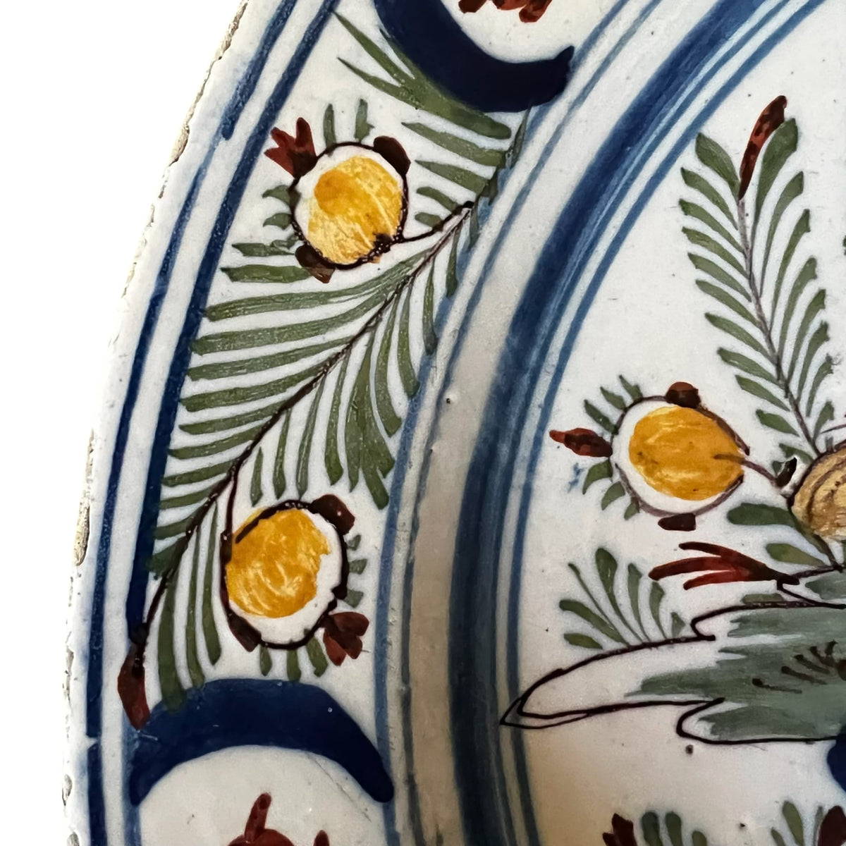 Détail de l'aile du plat ornée d'une frise continue de motifs floraux et végétaux stylisés.
