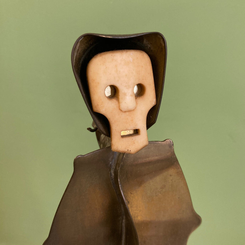 Sculpture représentant une vanité ou ne tête de mort en os, sur une base en métal en forme de flamme.