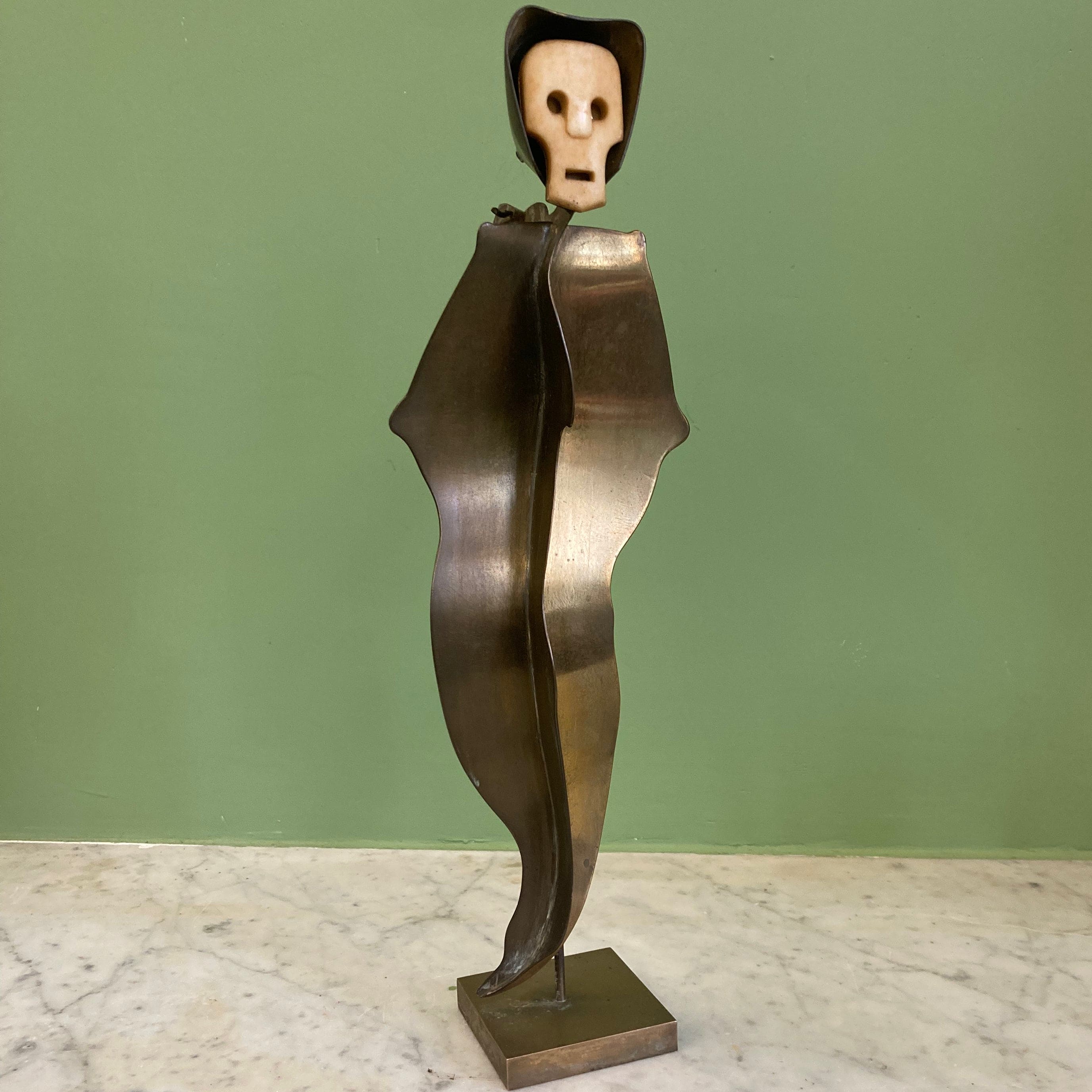 Sculpture représentant une vanité ou ne tête de mort en os, sur une base en métal en forme de flamme.