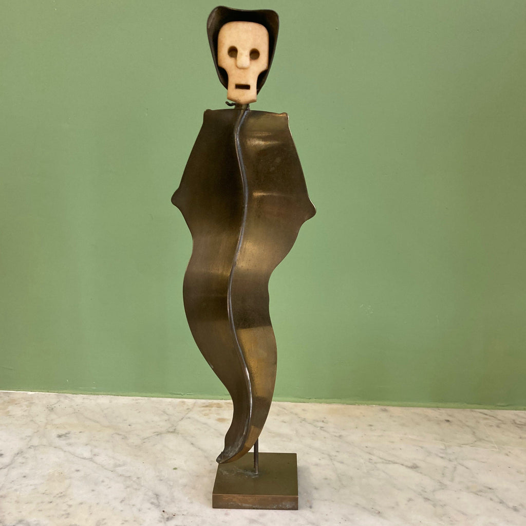 Sculpture représentant une vanité ou ne tête de mort en os, sur une base en métal en forme de flamme.