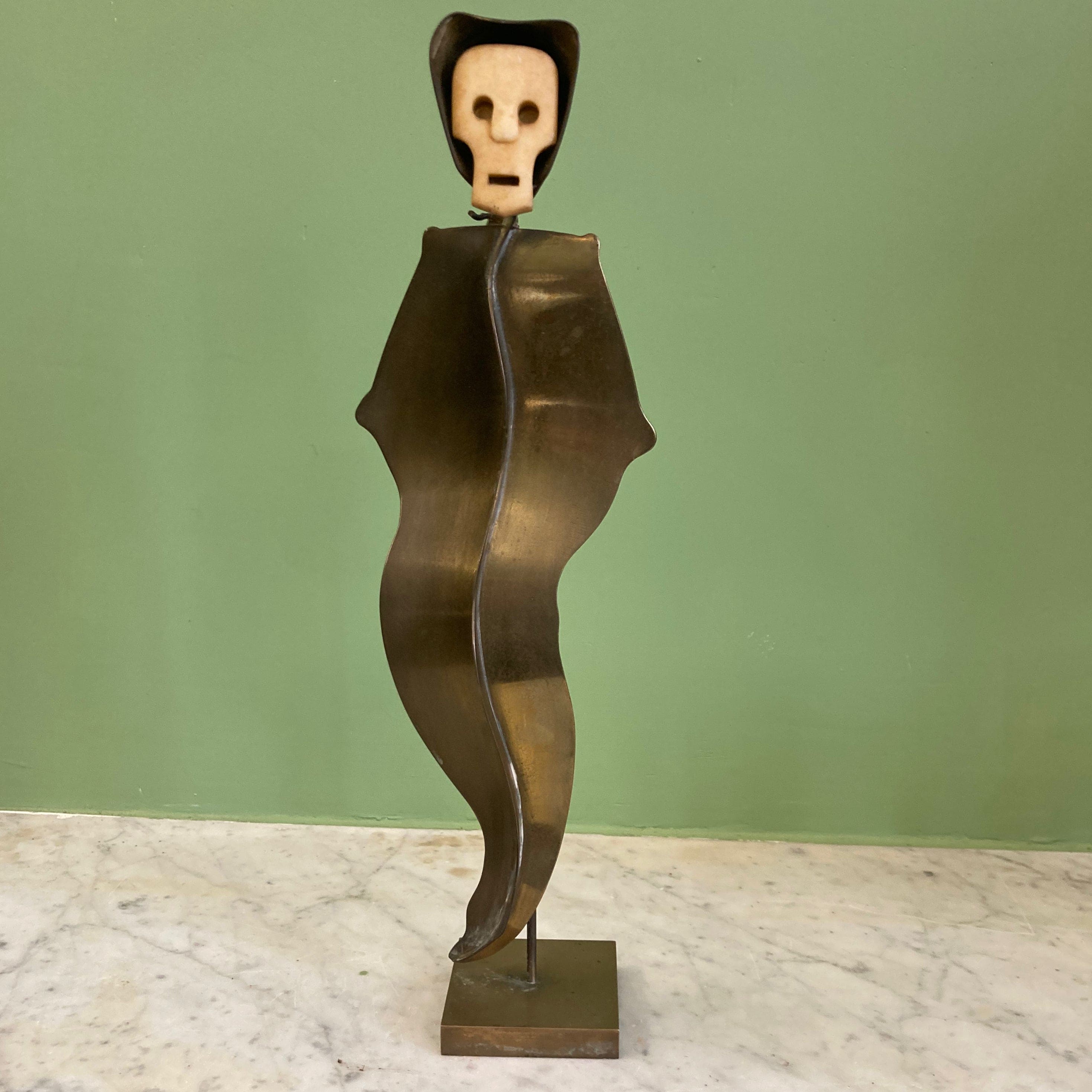 Sculpture représentant une vanité ou ne tête de mort en os, sur une base en métal en forme de flamme.