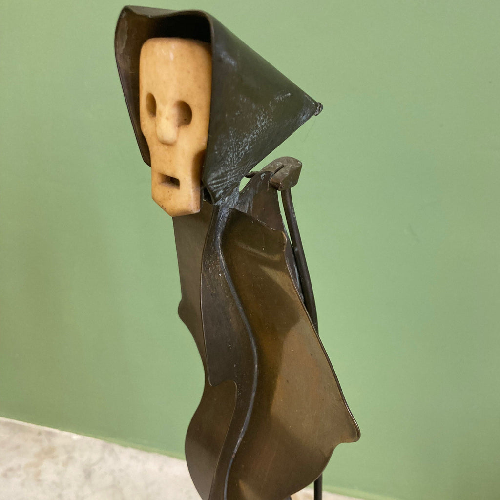 Sculpture représentant une vanité ou ne tête de mort en os, sur une base en métal en forme de flamme.