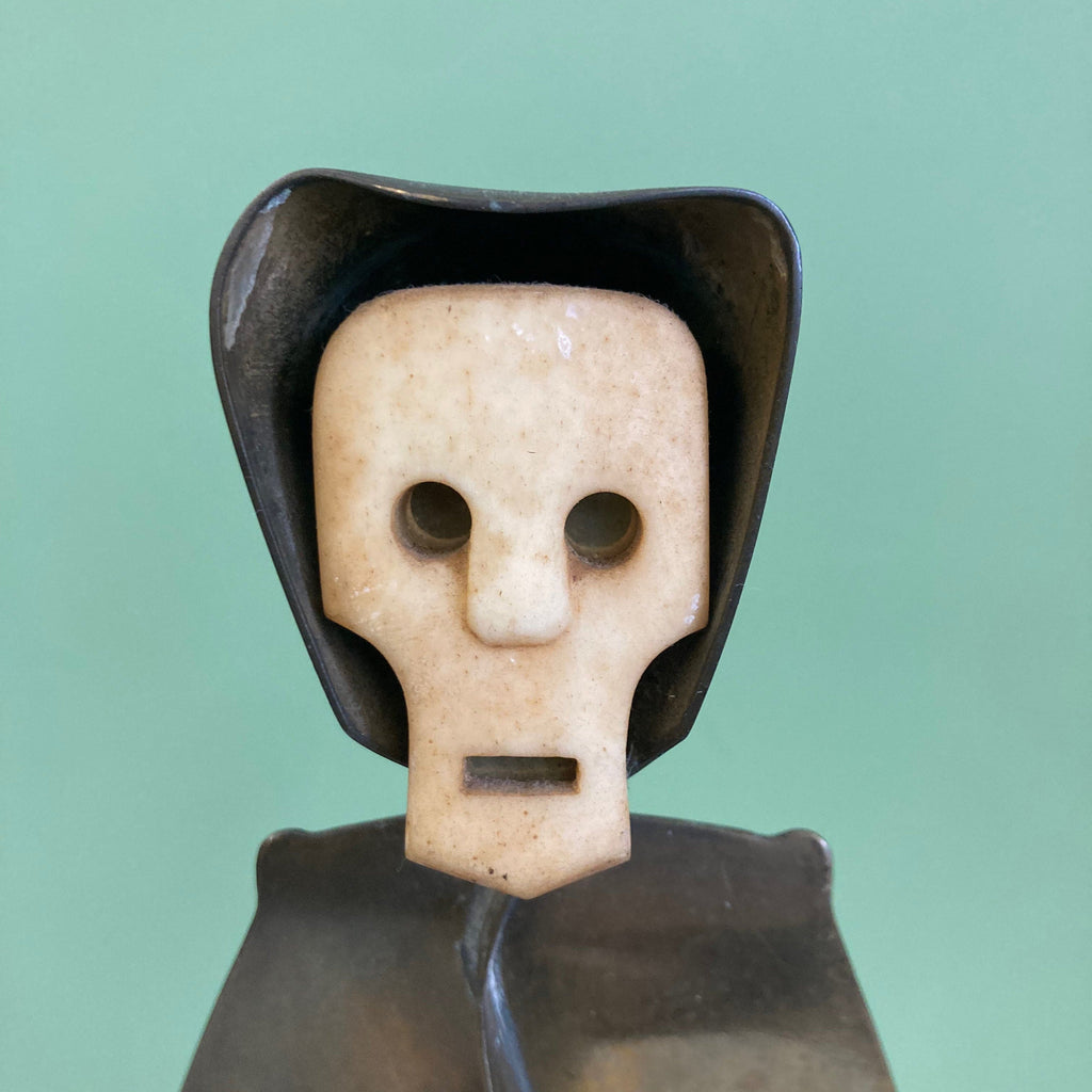 Sculpture représentant une vanité ou ne tête de mort en os, sur une base en métal en forme de flamme.