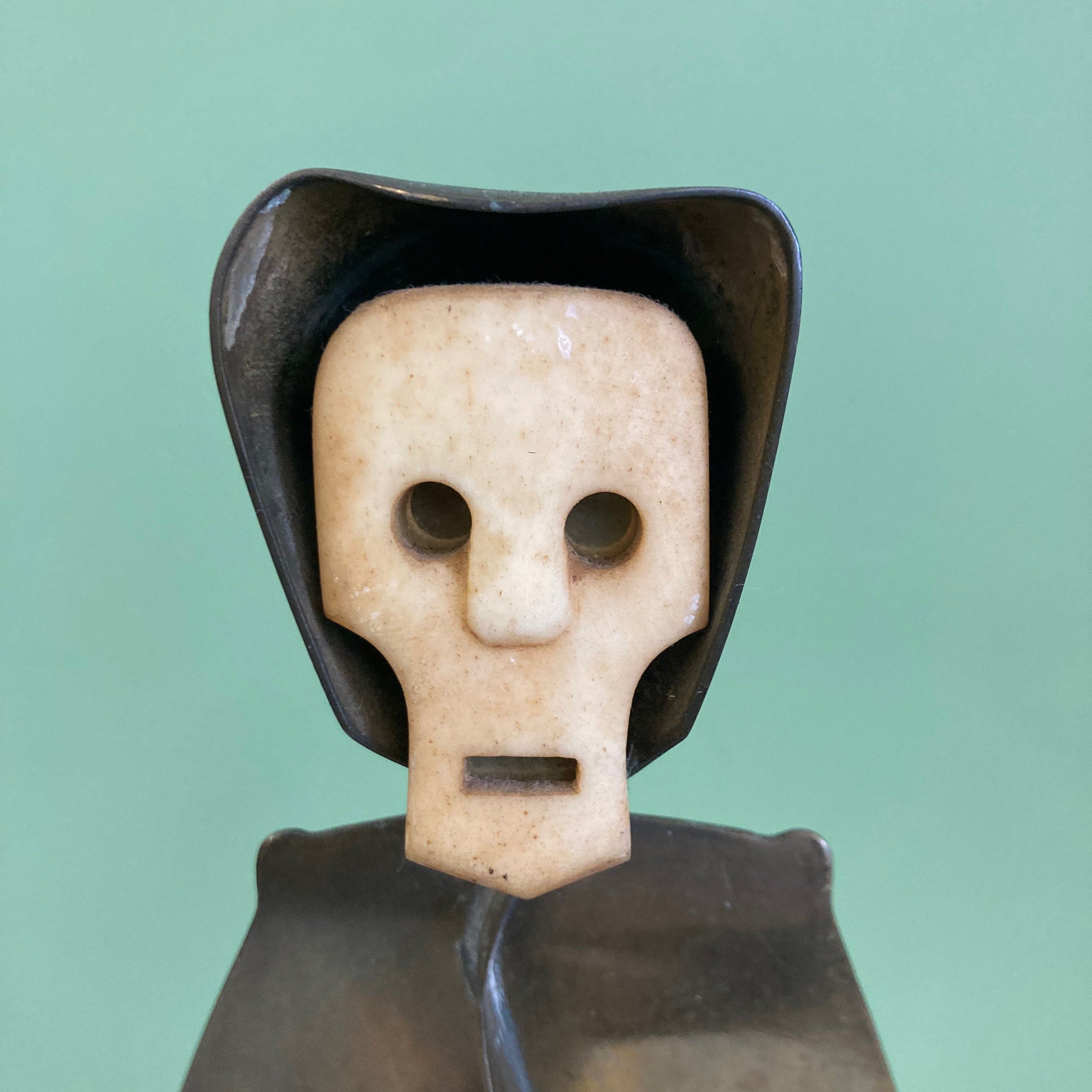 Sculpture représentant une vanité ou ne tête de mort en os, sur une base en métal en forme de flamme.